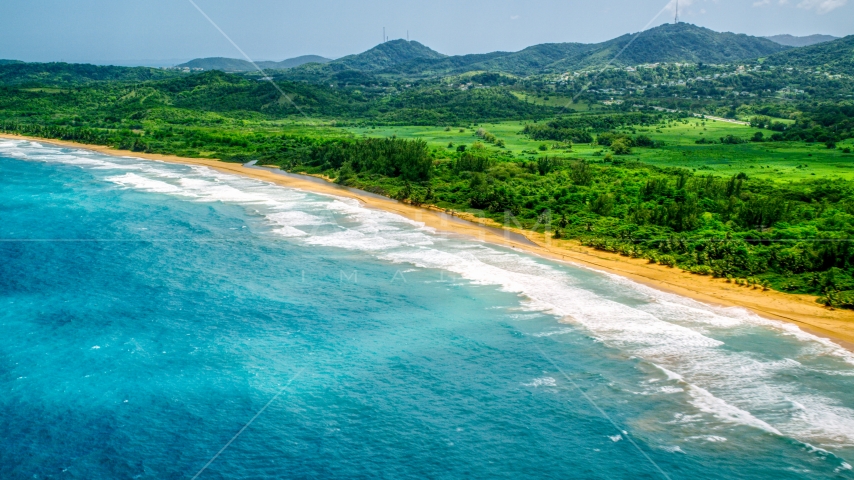 Waves rolling toward an empty beach and jungle in Luquillo, Puerto Rico Aerial Stock Photo AX102_052.0000138F | Axiom Images