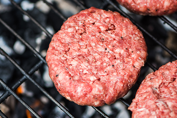 Raw burgers are cooked on the grill