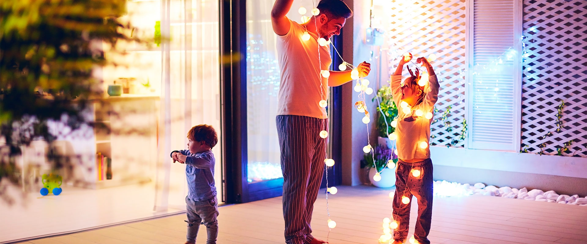 Padre e hijos adornando la casa con luces para una fiesta de Navidad.