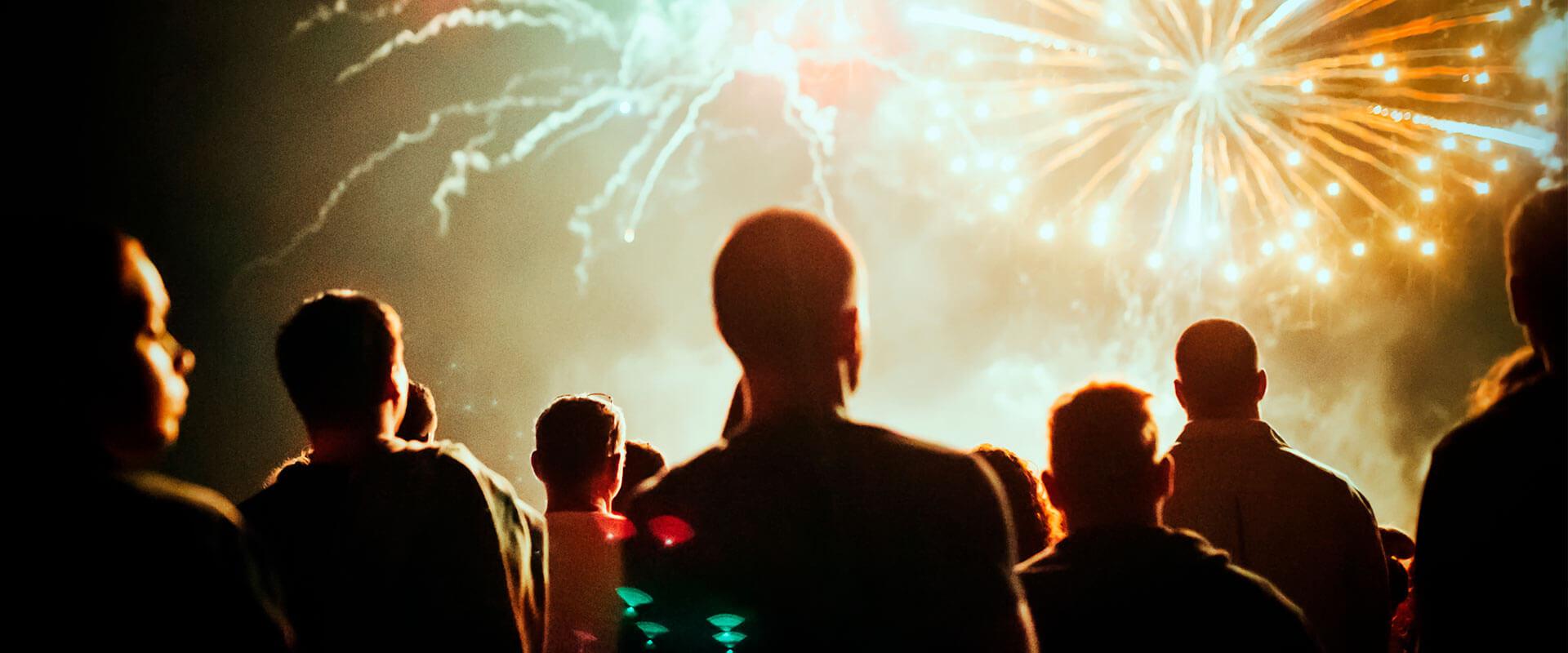 Personas viendo los fuegos artificiales en el cielo, durante la noche.