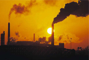sunset shown behind high carbon emission factory