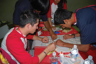 Four teenagers gathered around a table attempting to figure out a logic problem together.