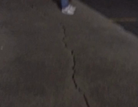 Guy takes a ball and breaks a window on a black car at night 