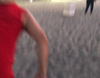 Red Shirt Tackles Trash Can on Beach Near Ferris Wheel