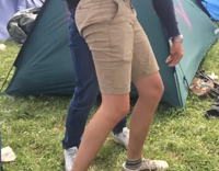 Guy in khaki shorts and blue sweater trips over tent