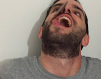 guy grey shirt trying to eat piece of chocolate 