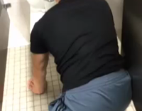 Drunk guy basketball shorts black shirt on knees in toilet stall