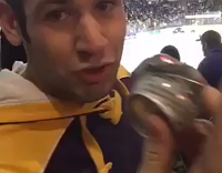 Guy in orange purple sweatshirt throws hockey puck during game 