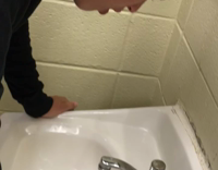 guy in black shirt throwing up on sink in  restroom 
