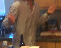 man with purple head piece breaks bottle on head