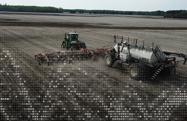 Aerial photo of tractor pulling an air seeder in a field in spring