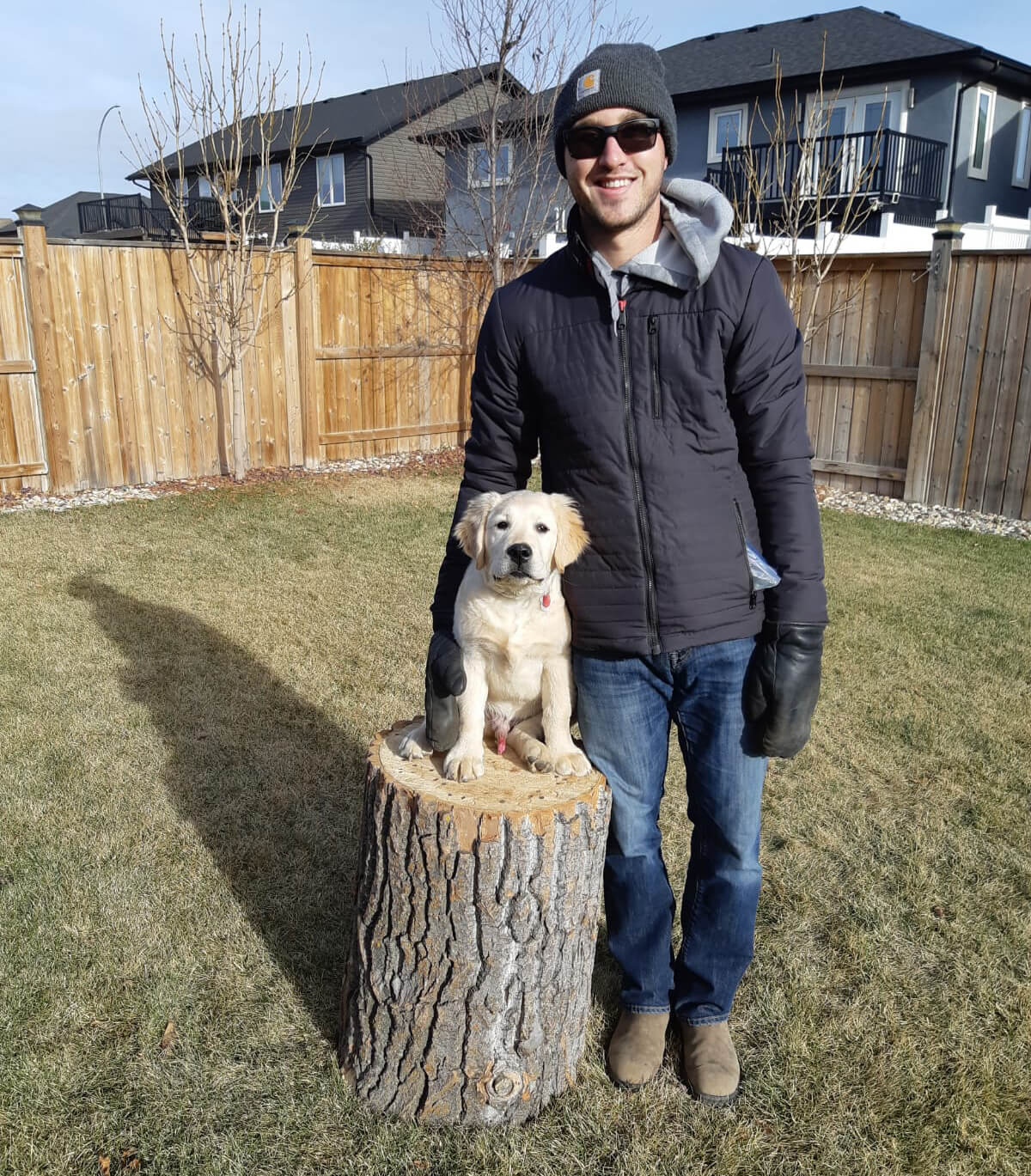 Mat Vercaigne with his puppy standing on a log in his backyard