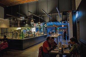 Preview of Mamnoon Restaurant - Image 10: Dining Room, Dining table, Kitchen, Steel, Concrete, Wood, Glass, Window, Sliding Door, Glass Door, Stainless Steel, Tile, Restaurant, Entry, Exposed Structure, Structure Steel.