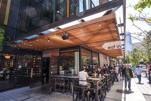 Preview of Mamnoon Street - Image 4: Restaurant, steel, Wood, Concrete, Glass, Window, Storefront, Entry, Door, Dining Table, Outdoor, Street.