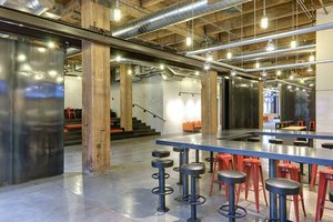 Preview of Payscale - Image 0: industrial, modern, structure wood, structure steel, black steel, concrete floor, open ceiling, exposed ductwork, pendant lights, communal table, bar stools, wooden beams, metallic surfaces, interior design, urban, exposed pipes, red accents, multi-level seating, concrete wall, workshop style, gathering space, informal seating, minimalistic lighting, exposed ceiling, event space, historic.