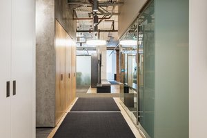 Preview of Undead Labs - Image 22: plywood flooring, exposed ceiling, ductwork, track lighting, modern, hallway, office, glass partition, exit sign, wood, concrete wall, structure concrete.