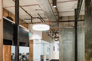Preview of Undead Labs - Image 2: open floor plan, industrial design, exposed piping, concrete wall, glass partition, track lighting, modern furniture, wood accents, office space, neutral colors, carpet flooring.