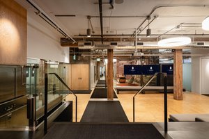 Preview of Undead Labs - Image 13: open floor plan, wood beams, concrete floor, exposed ductwork, modern lighting, glass partition, neutral color palette, railing.