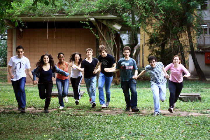 Nine young adults running outdoors towards the camera