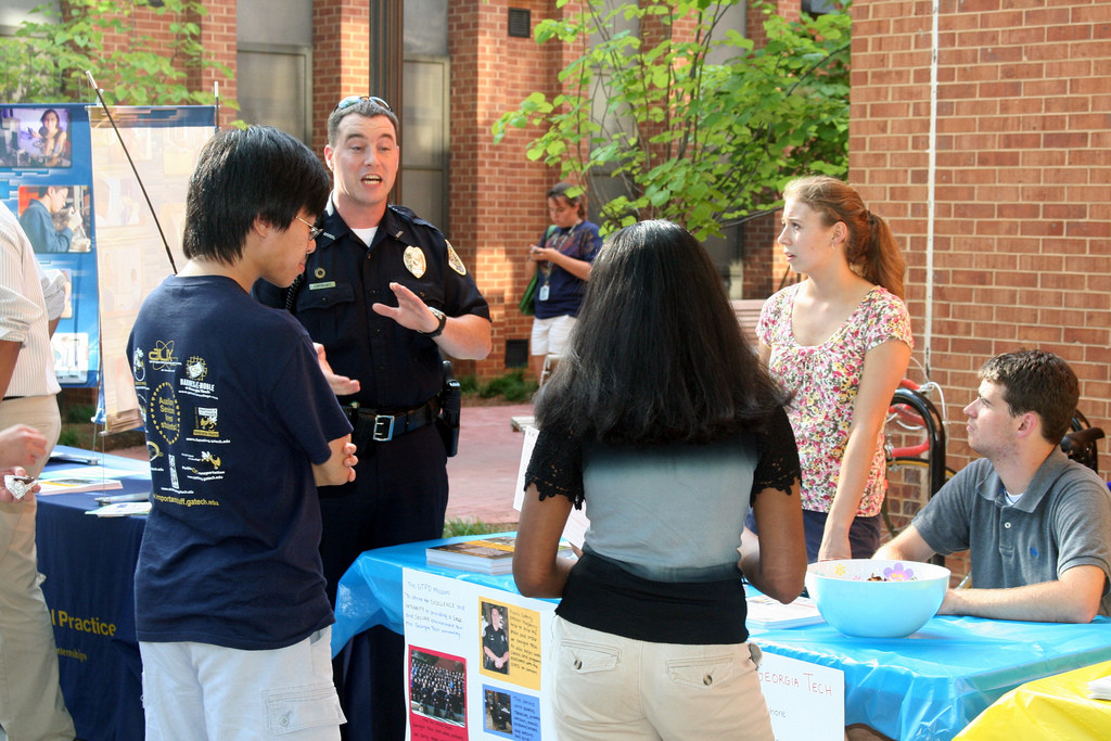 Four college students are listening to a policeman talk.