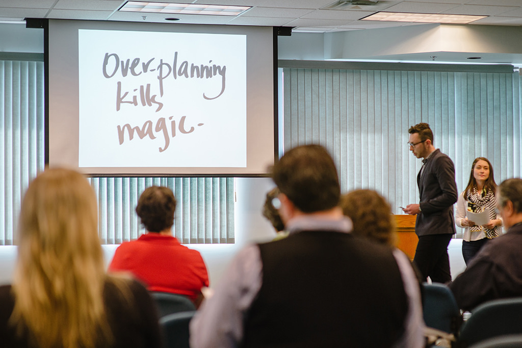 Students giving presentation in a classroom. An overhead projector displays the text "Overthinking kills magic."