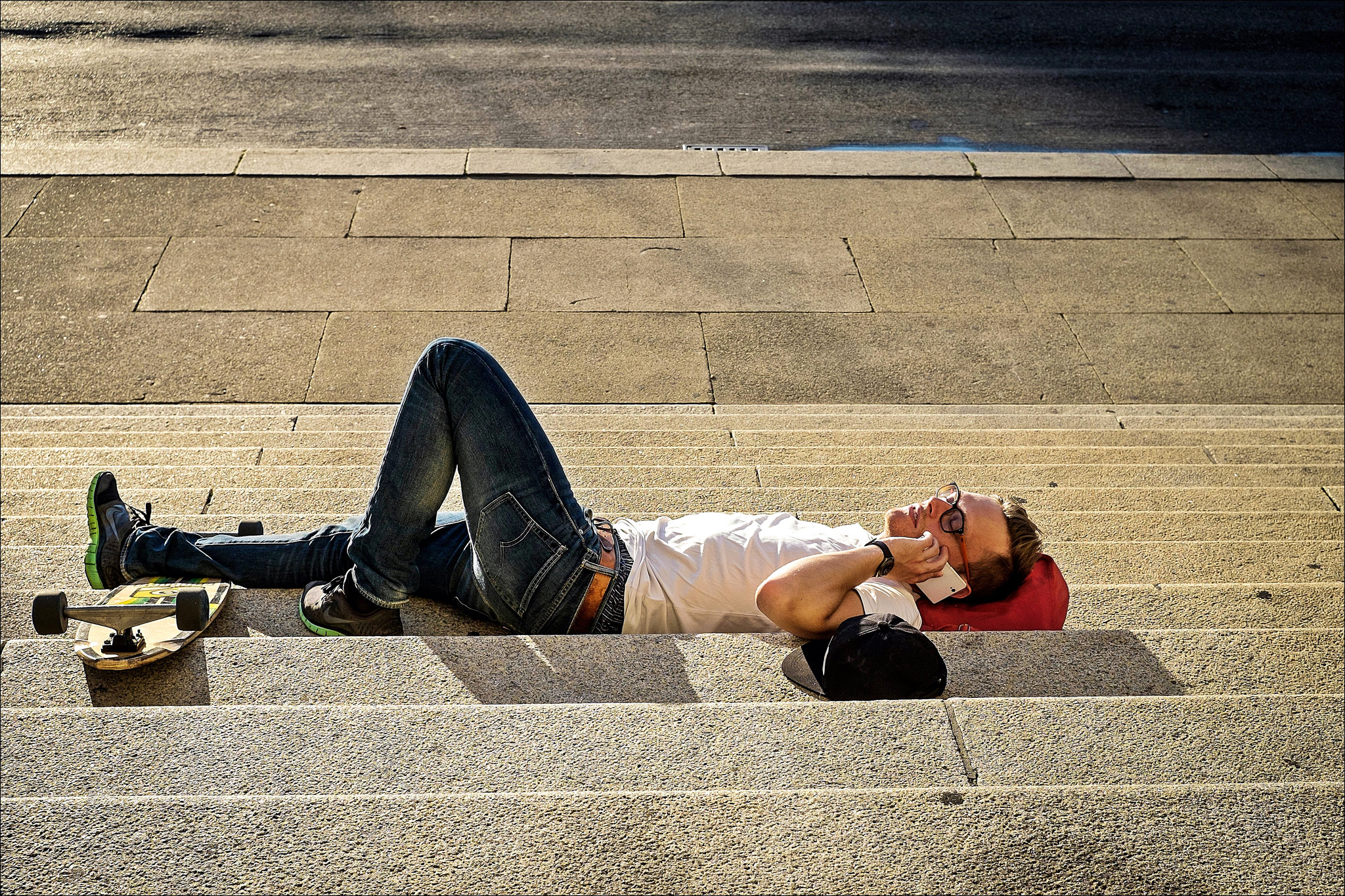 Man lies on his back while talking on the phone