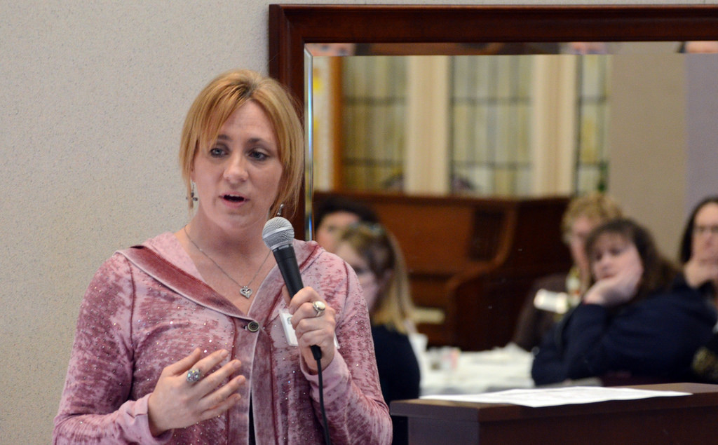 Photo of a woman holding a mic, talking to a group of people in a substance abuse program.