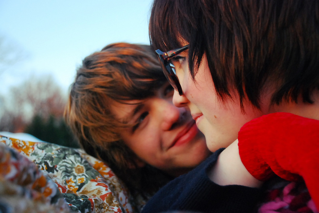 Closeup of a young man embracing and smiling at a young woman.