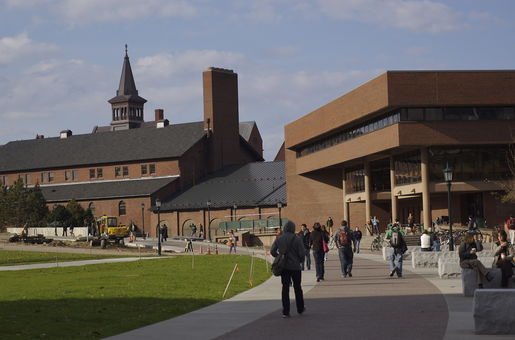 Photo of a college campus with students walking to and from class on a paved path.