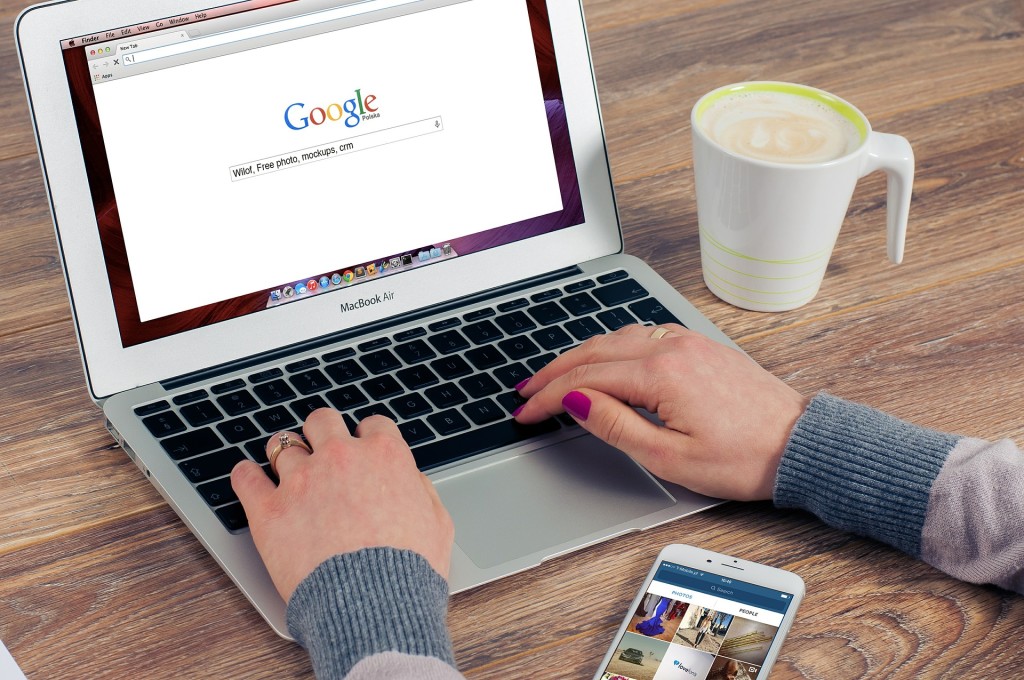 Photo of a woman's hands on a laptop keyboard; the word GOOGLE is on the screen.