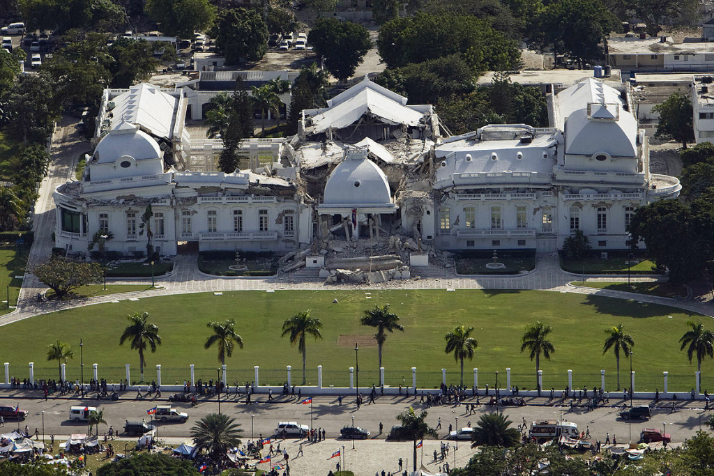 A large palace by a beach. Some of the walls have collapsed.