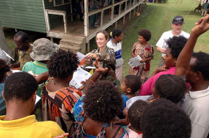 Soldado americano distribuindo apostila explicando os sintomas da tuberculose aos residentes locais no Bunabun Health Center em Madang, Papua Nova Guiné.