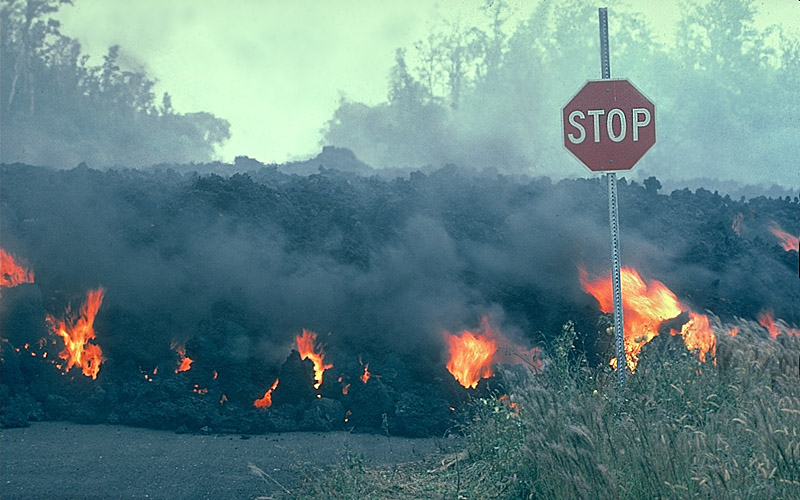 Fluxo de lava com fogo visível movendo-se atrás de um sinal de stop.