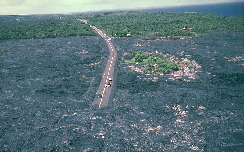 Rodovia completamente cercada e parcialmente coberta de lava. A lava se estende por pelo menos um quilômetro por todos os lados.