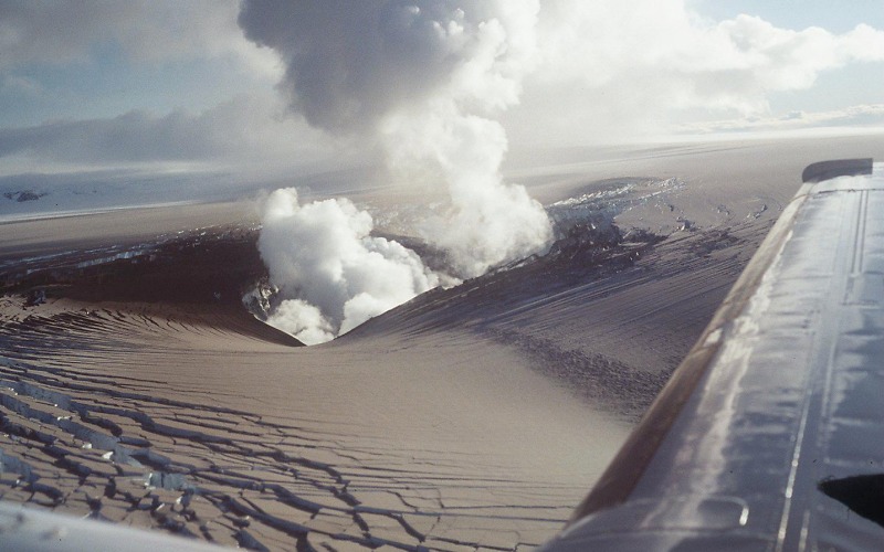 Photograph taken from an airplane; there is a still a huge plume coming from the volcano.