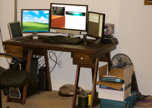 desk with three computer monitors on top