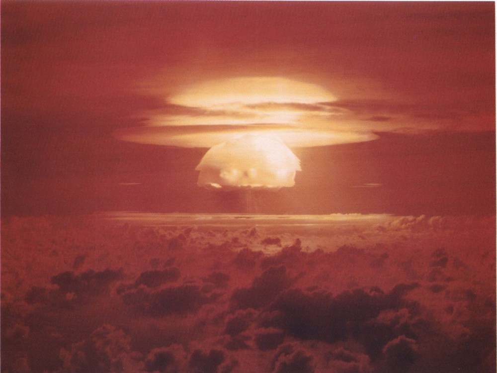 The mushroom cloud of an atomic explosion rising above the clouds.