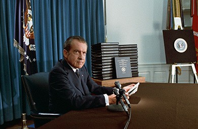 A photograph shows President Nixon seated at a desk by several microphones, holding papers as he prepares to address the nation.