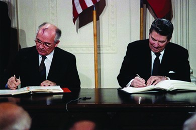 A photograph shows Mikhail Gorbachev and Ronald Reagan sitting beside one another as they sign the INF Treaty.