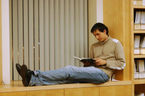 Man sitting in a window seat reading