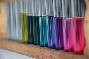 Row of metallic rainbow-colored tubes with silver tops.