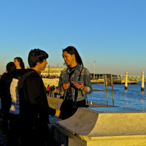  Hombre y mujer jóvenes hablando en un muro marino lleno de gente