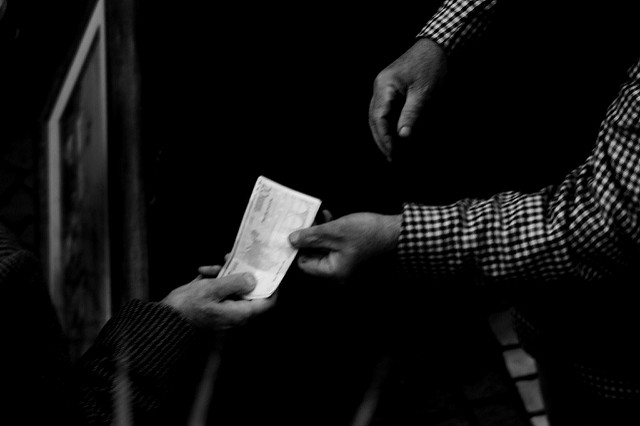 Black and white aerial shot of hands exchanging money