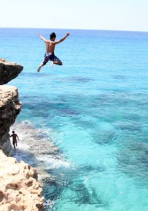 Person jumping from a rock into water from a great height.