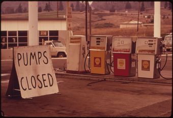 A photo of a gas station in 1973 with a sign next to the pumps saying "PUMPS CLOSED."