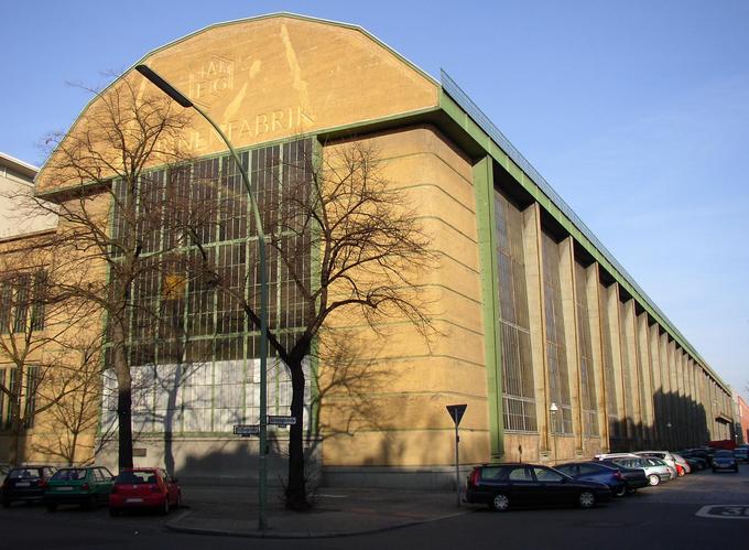 Image of the outside of the factory. There are tall glass and steel walls on the side.