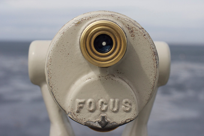 A picture of mounted binoculars with the word "focus" and an arrow at the bottom.