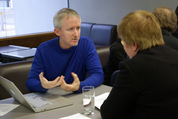 A picture of a man and woman sitting at a table. The man is talking while the woman listens.