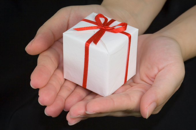 A woman holds a small present in her hands.