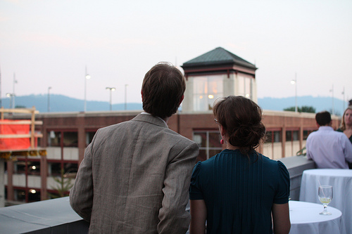 A man and woman looking into the distance from a rooftop restaurant.